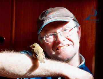 Skipper mit Vogel auf dem Arm